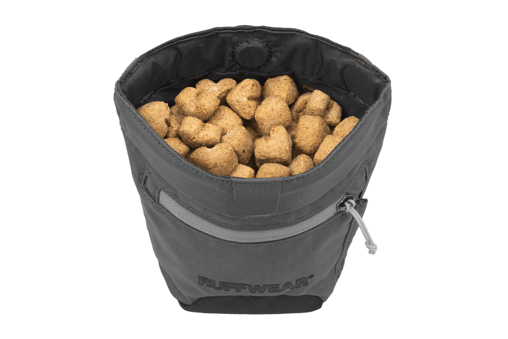Graue Treat Trader™ Leckerlitasche von Ruffwear, gefüllt mit Keksen, mit Reißverschluss und stabiler Standform.