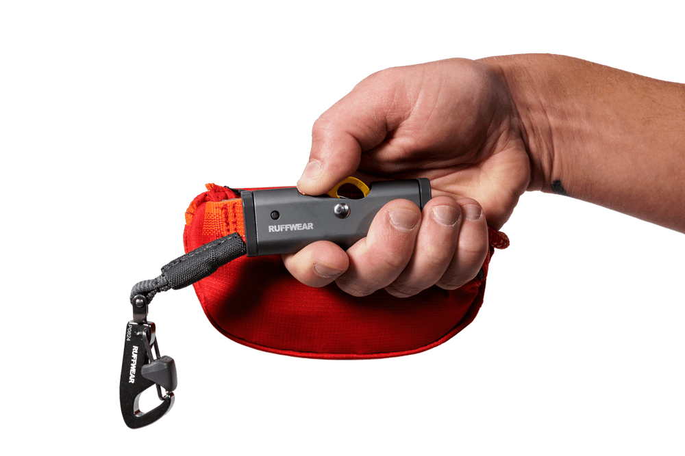 Hitch Hiker™ Hundeleinenhalter in der Hand, mit roter Tasche und Karabiner, ideal für unterwegs.