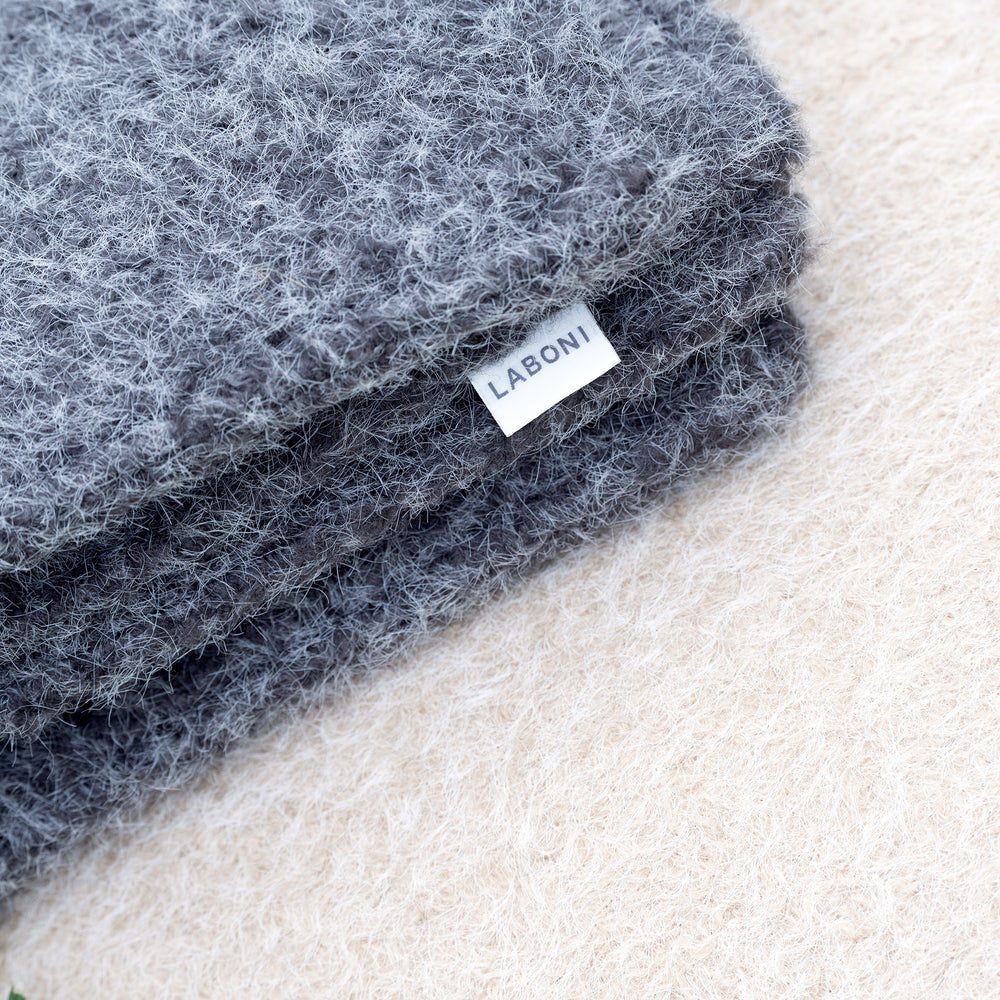 Graue Reisedecke FELTRO aus flauschigem Material mit LABONI-Etikett auf neutralem Hintergrund.