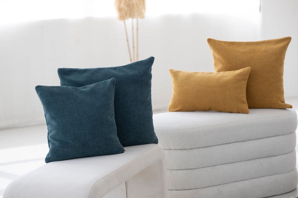 Vier Kissenbezüge in Blau und Gold auf gepolstertem Untergrund, ideal für gemütliche Wohnräume.