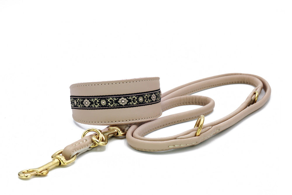 Beige Hundeleine mit schwarzer floraler Borte und goldfarbenem Karabinerhaken im Fokus.
