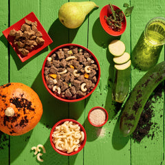 Vegane Hundernahrung GREEN PLANET Kein Rind, schmackhafte, pflanzliche Zutaten auf grüner Holzoberfläche präsentiert.