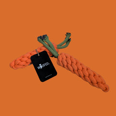 Zwei orangefarbene Kauknochen in Karottenform mit grüner Kordel und WOOFED.-Tag, ideal für spielende Hunde.