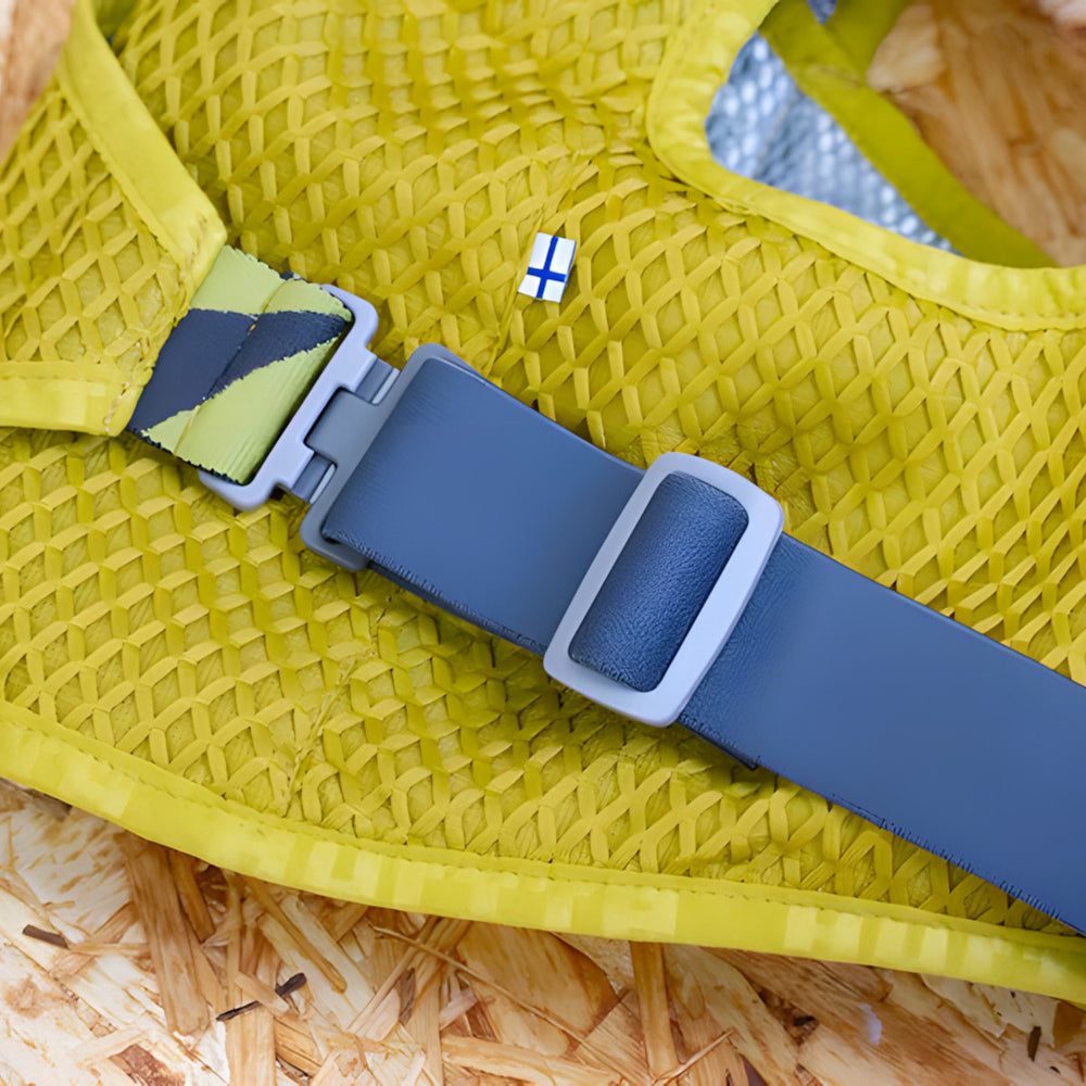 Gelbes meshähnliches Kleidungsstück mit blauem Gurt und Schnalle sowie finnischer Flagge im Hintergrund.