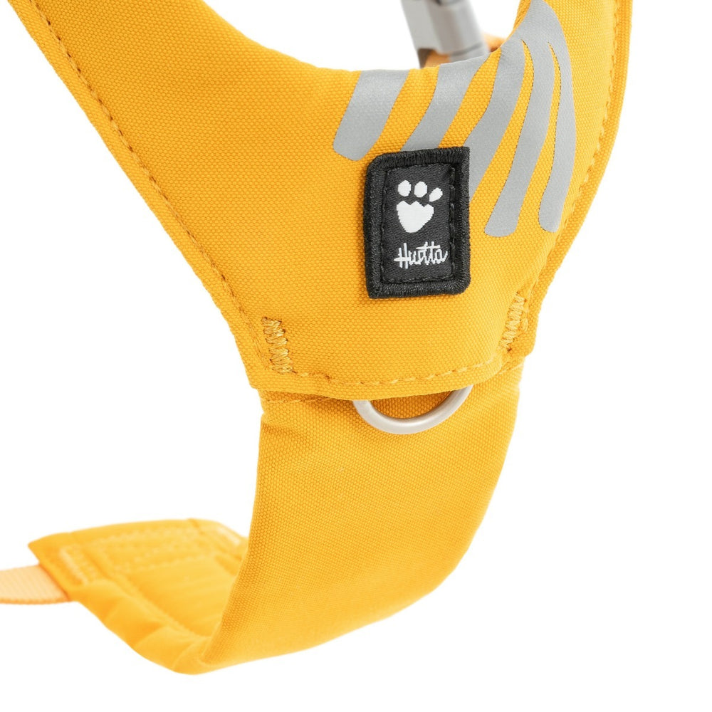 Gelbes Hundegeschirr Seeker mit reflektierenden Elementen und schwarzem Hutt-Logo, ideal für sichere Spaziergänge.