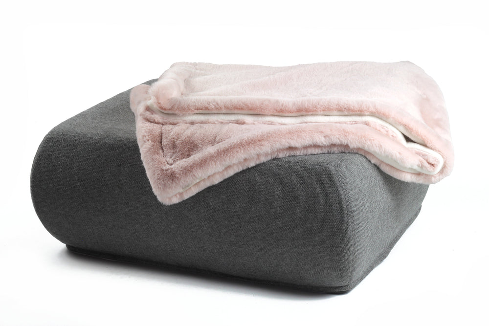 Grauer Hocker mit abgerundeten Kanten und einer flauschigen, hellrosa Wohndecke aus Webpelz.