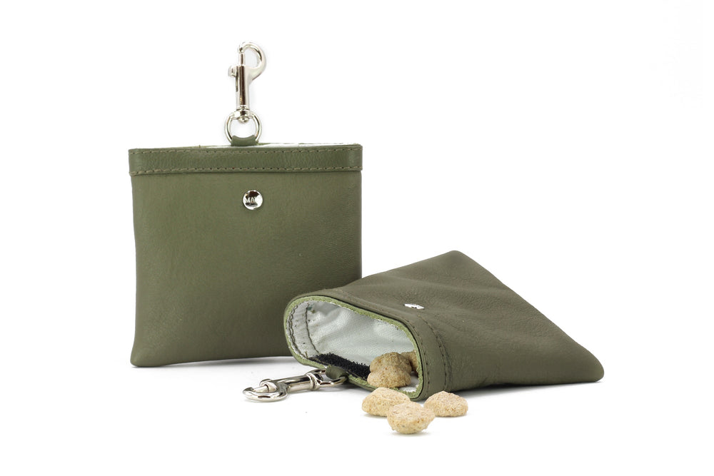 Olivgrüner Leder-Leckerli-Beutel mit Karabinerhaken, offen mit Snacks davor.