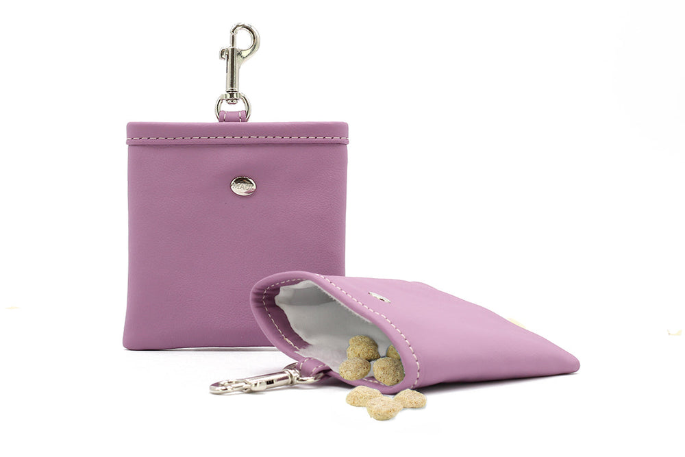 Lila Schlüsselanhänger-Portemonnaie aus Leder mit Hundekeksen im Inneren, leicht geöffnet und zur Seite geneigt.