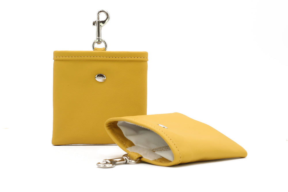 Gelbe Leder-Geldbörse mit Clipverschluss und dazu eine offene, gelbe Stofftasche.