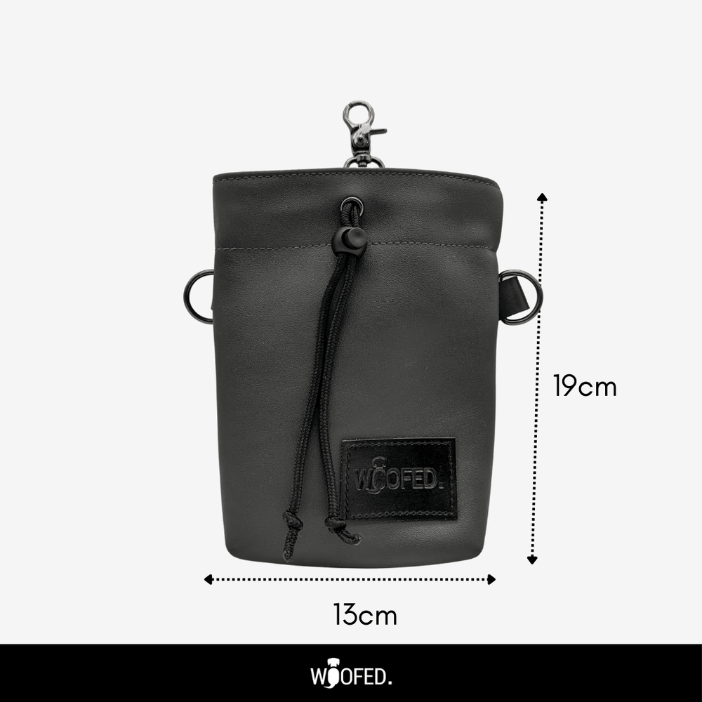 Schwarze Kunstledertasche mit Kordelzug und Halteringen, ideal für Leckerlis. Höhe: 19 cm, Breite: 13 cm.