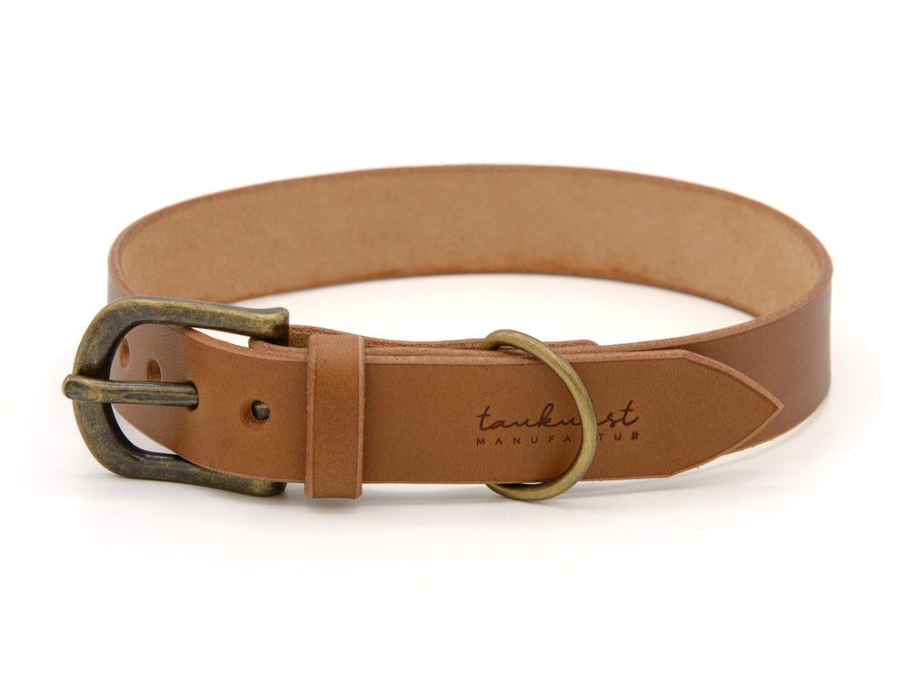 Braunes Welpenhalsband aus Leder mit klassischer Metallschnalle und dezentem Logo auf der Innenseite.