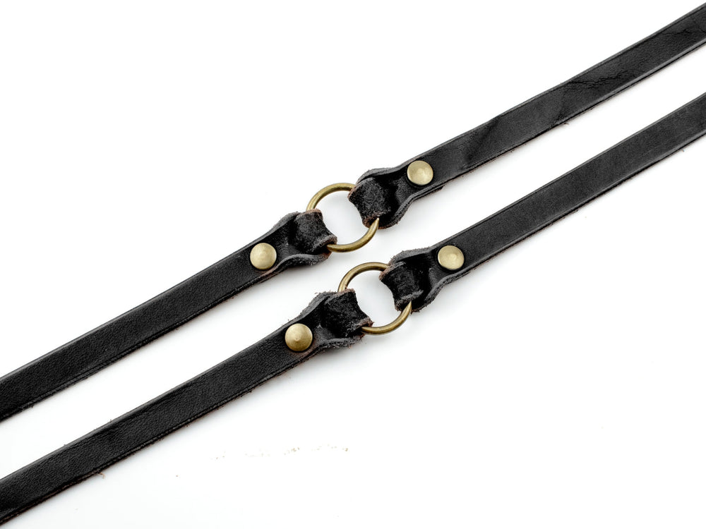 Schwarze Lederleine mit messingfarbenem Ring und Druckknöpfen für Hunde, ideal für das Training im Wald.