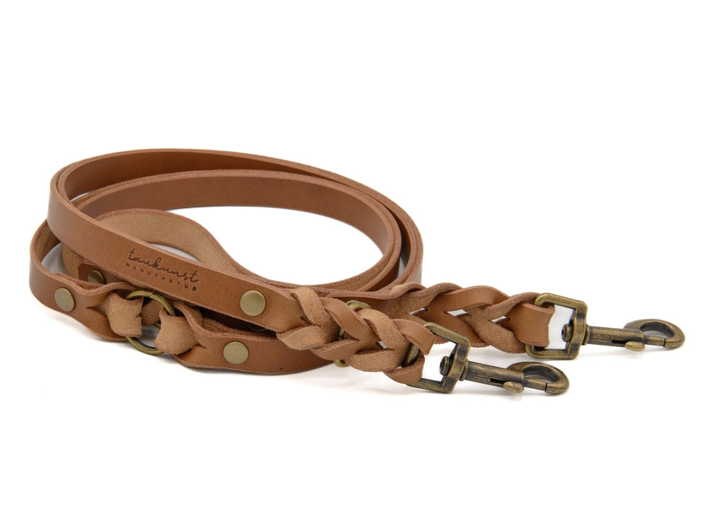 Zwei braune Leder-Hundeleinen, eine geflochten und eine glatt, beide mit bronze-farbenen Karabinerhaken.