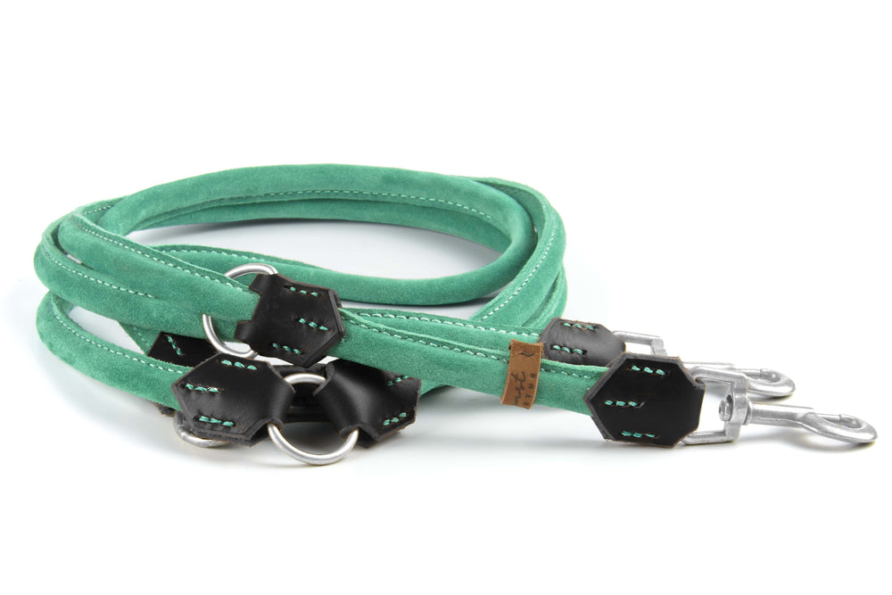 Grüne Wildlederleine für Hunde mit schwarzen Lederdetails und zwei Metallkarabinern, doppelt gefaltet und oval geformt.