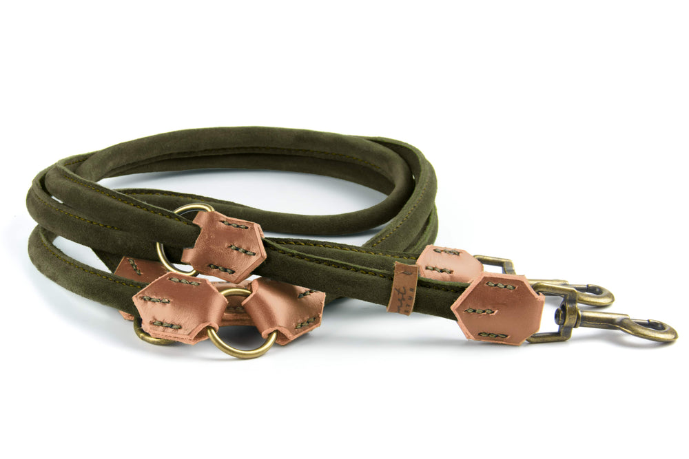 Grüne Wildlederleine mit braunen Lederakzenten und goldenen Beschlägen, gefaltet und mit Karabinerhaken sichtbar.