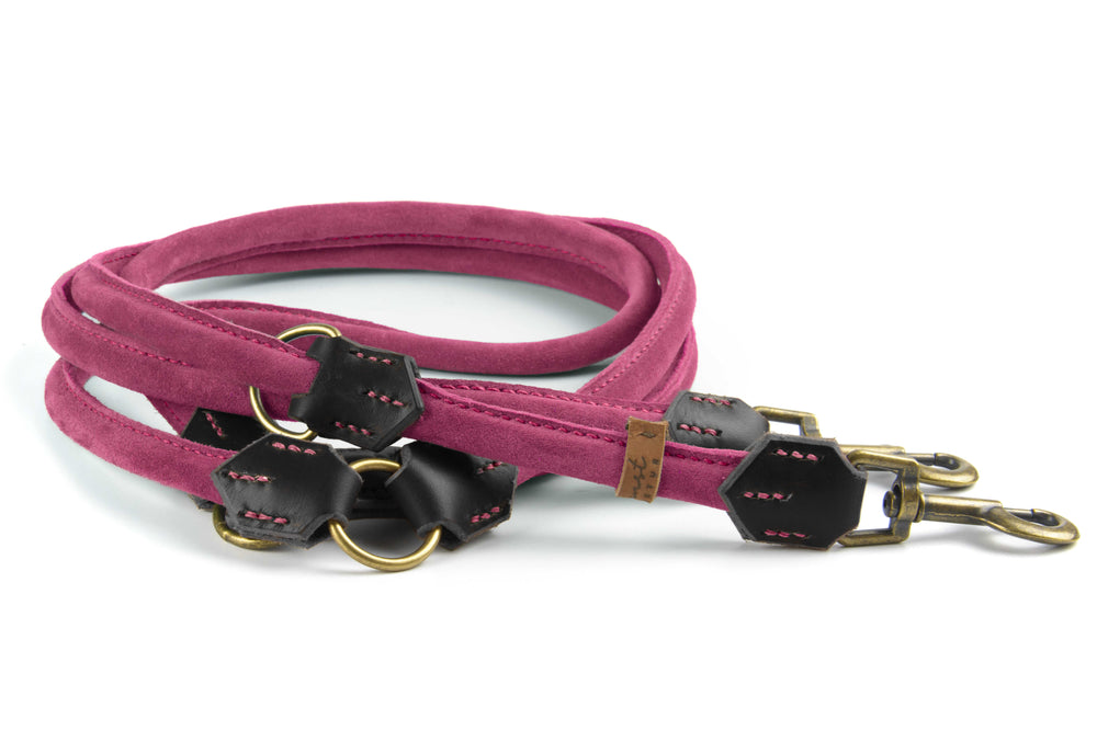 Pinke Wildlederleine mit schwarzen Lederakzenten und Karabinerhaken, elegant zusammengerollt für stilvolle Hundebesitzer.
