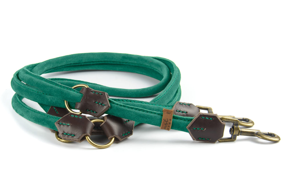 Grüne Wildlederleine für Hunde mit braunen Lederverbindungsstücken und metallenen Karabinerhaken. Elegantes, weiches Design.
