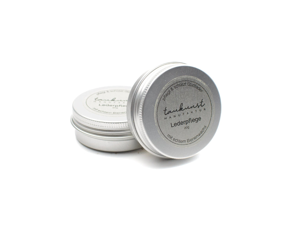 Silberne Dosen mit Etikett "Lederpflege" und Hinweis auf reichhaltiges Bienenwachs für optimale Lederpflege.