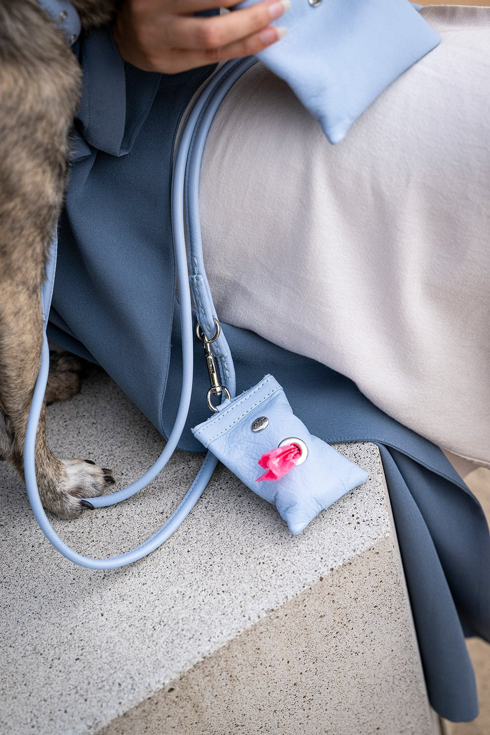 Hellblaue Tasche mit Trageriemen und dekorativer Applikation, ideal für Schlüssel oder Kleingeld.