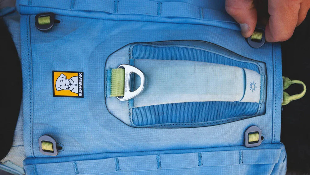 Blaue Hundeweste von Ruffwear mit Haltegriff und Befestigungselementen, inklusive Markenlogo.
