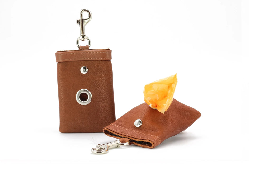 Brauner Hundekotbeutel-Holder aus Kunstleder mit Karabinerhaken und orangefarbenem Beutel, kompakt und praktisch.