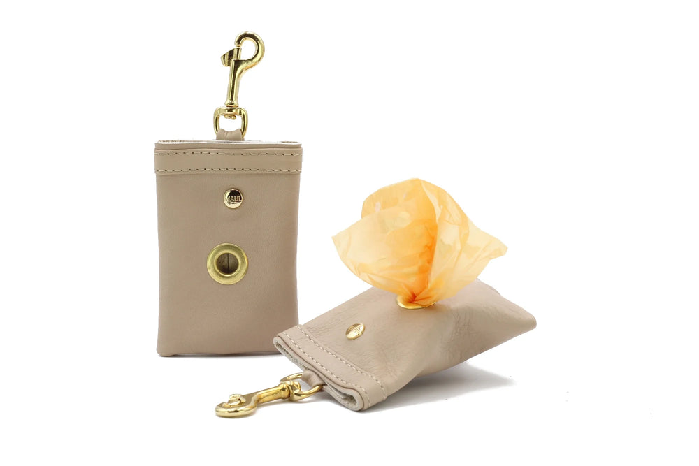 Beiger Leder-Taschenhalter mit goldenen Karabiner und orangefarbenem Beutel, ideal für Hundekotbeutel.