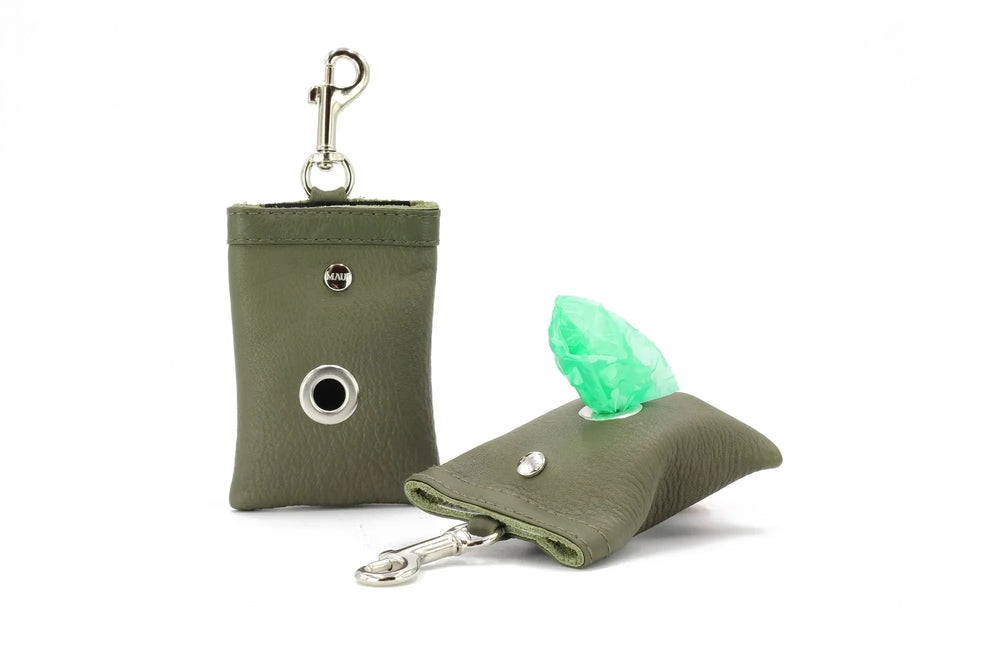Kleiner grüner Hundekotbeutelhalter aus Kunstleder mit Metallkarabiner und geöffneter Beutelöffnung.
