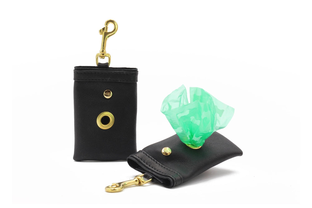 Schwarze Hundekotbeutelspender aus Kunstleder mit goldenen Karabinerhaken und grünen Kotbeuteln.
