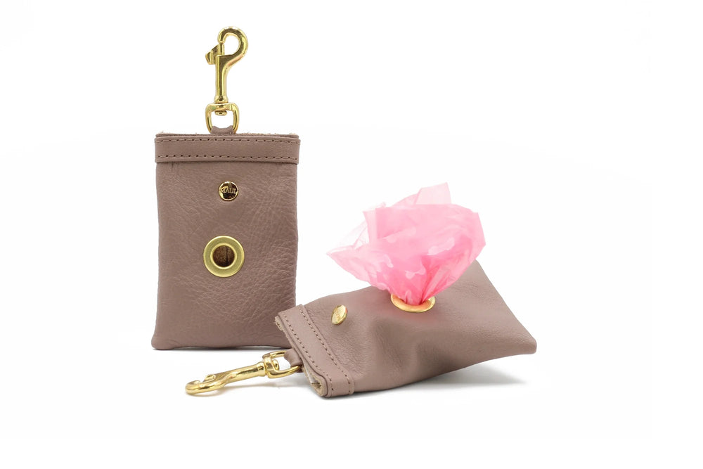 Zwei braune Hunde-Kotbeutel aus Leder mit Karabinerhaken und rosa Tüte für Hundekot. Ideal für Hundebesitzer.