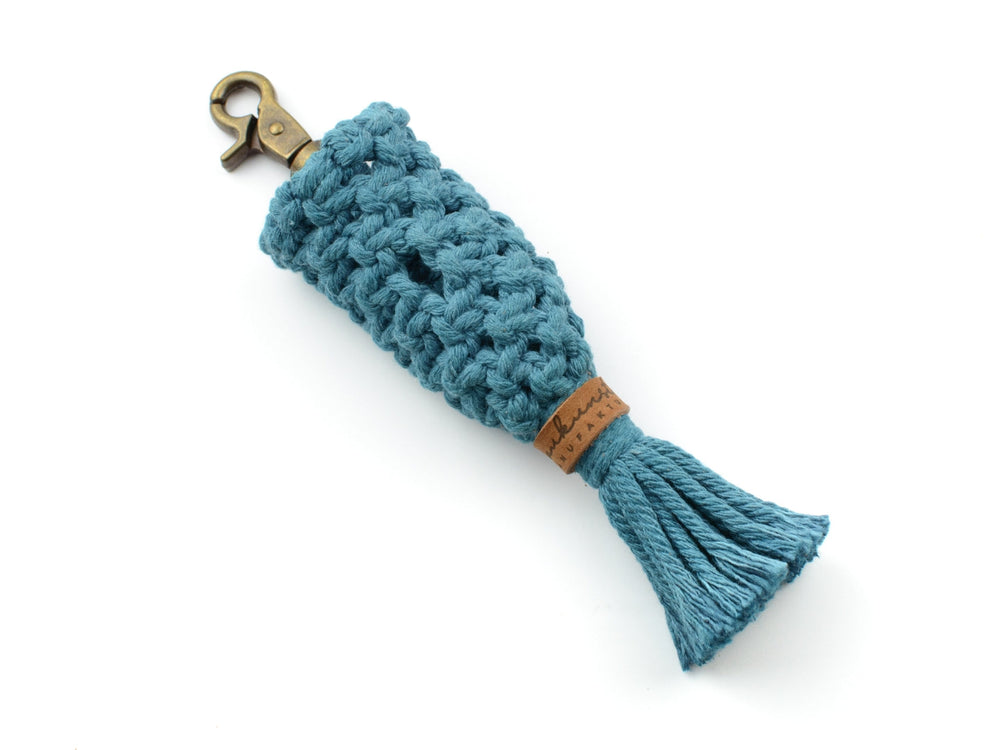 Azurblauer Makramee-Schlüsselanhänger mit Clip und quastenartiger Verzierung, plus brauner Lederapplikation.