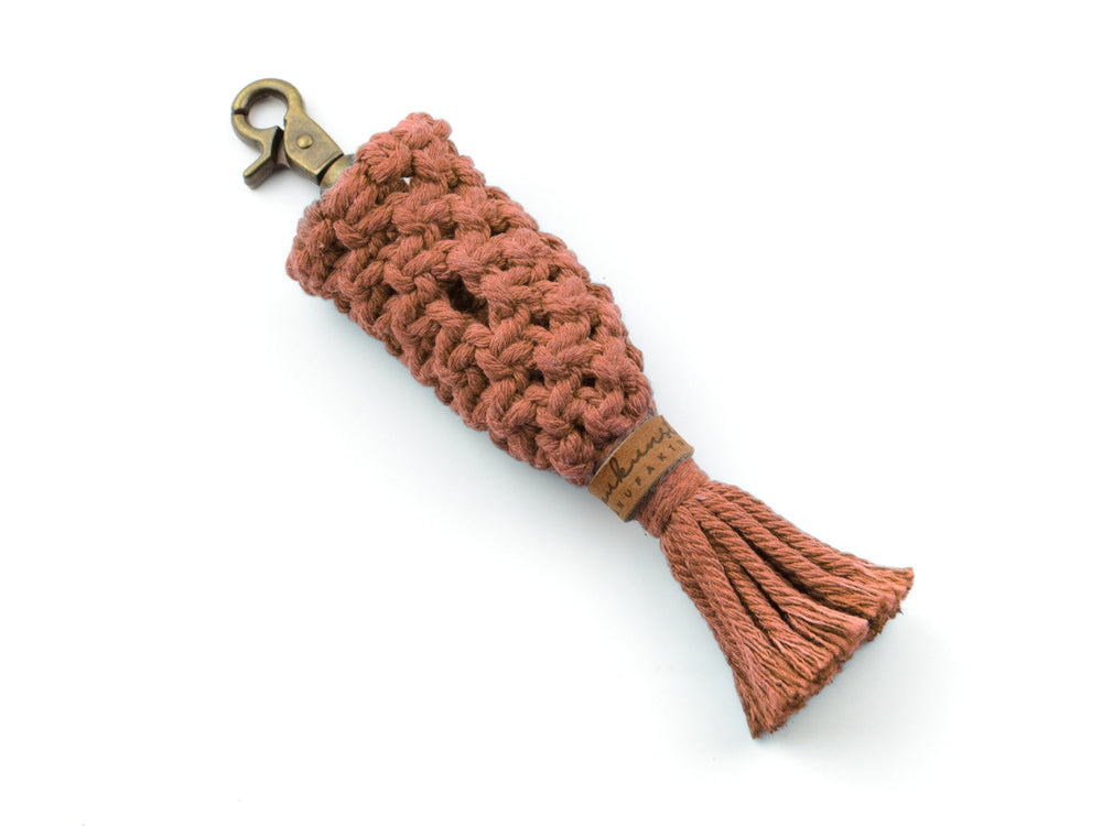Handgefertigter Schlüsselanhänger in warmem Rosa mit braunem Lederpatch und geflochtenem Material, stilvoll und praktisch.