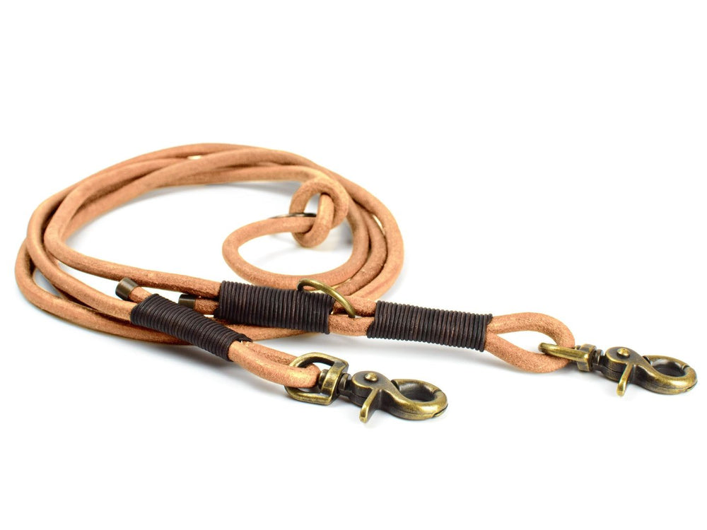 Doppelte Hundeleine aus robustem, hellbraunem Rundleder mit gummierten Griffen und Karabiner-Verschlüssen. Ideal für Waldläufer.
