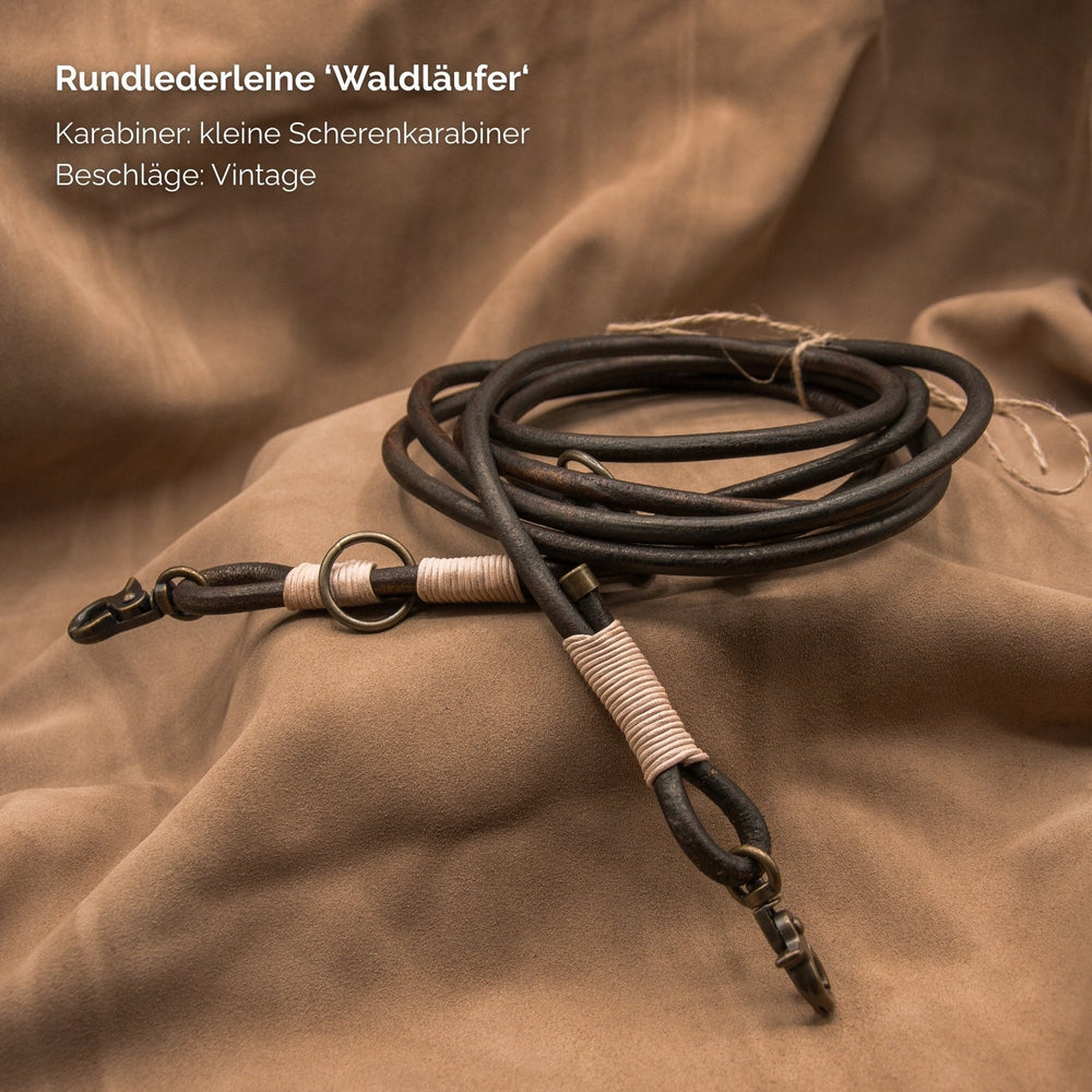 Runde Lederleine "Waldläufer" in hochwertigem Leder mit Scherenkarabiner und vintage Beschlägen auf neutralem Hintergrund.