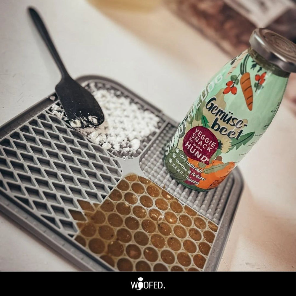 Graue Silikon-Schleckmatte mit Fächern und Gemüse-Beet Veggie Snack Flasche für Hunde.