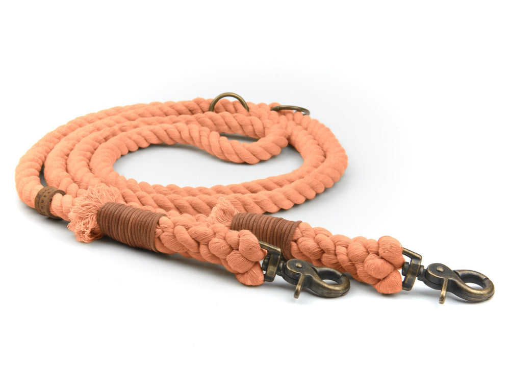 Orangefarbene geflochtene Hundeleine mit metallischen Karabinerhaken und braunen Lederakzenten. Ideal für Hundehalter.