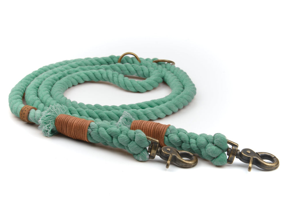 Grüne geflochtene Tauleine mit Karabinerhaken und braunen Lederdetails auf weißem Hintergrund.