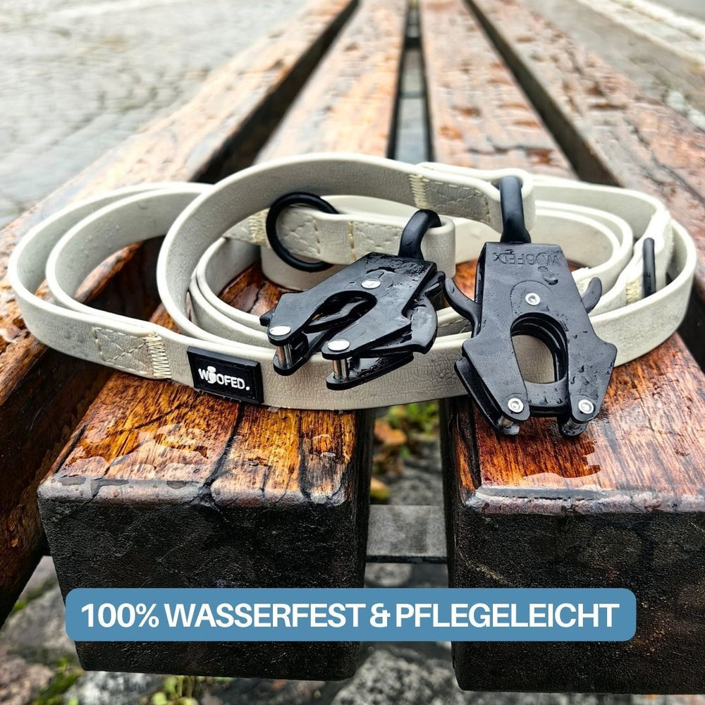 Verstellbare WOOFLEX® Führleine mit Froschkarabiner für Hunde, auf einer Holzbank dargestellt. Strapazierfähiges, helles Material.