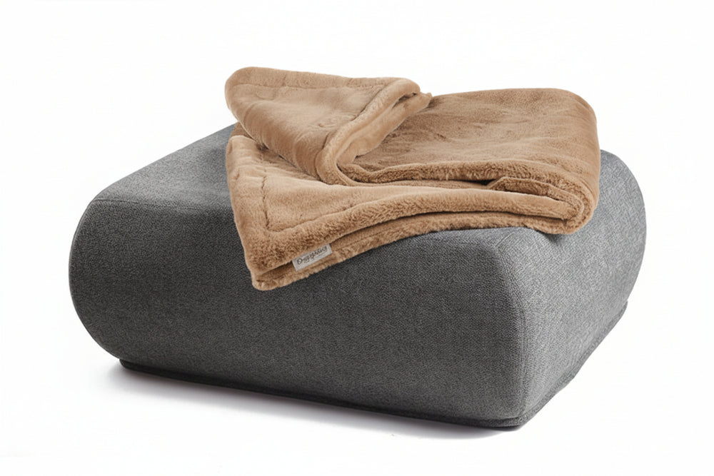 Gemütlicher grauer Hocker mit runder Form, dekoriert mit einer gefalteten braunen Fleece-Wohndecke.