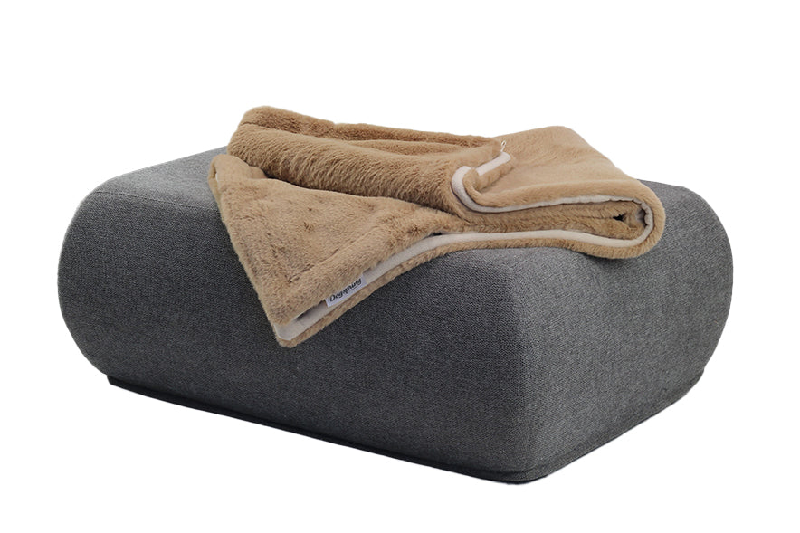 Weiche, braune Wohndecke aus Webpelz liegt ordentlich auf einem grauen, geschwungenen Hocker.