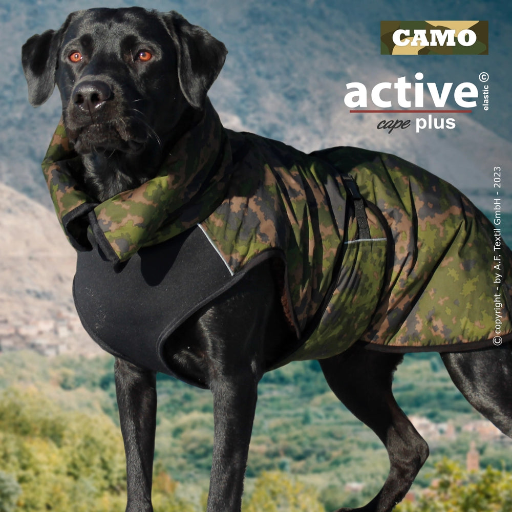 Schwarzer Labrador mit modernem Camouflage-Hundemantel in bergiger Landschaft, der Bewegungsfreiheit bietet.