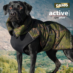 Schwarzer Labrador mit modernem Camouflage-Hundemantel in bergiger Landschaft, der Bewegungsfreiheit bietet.