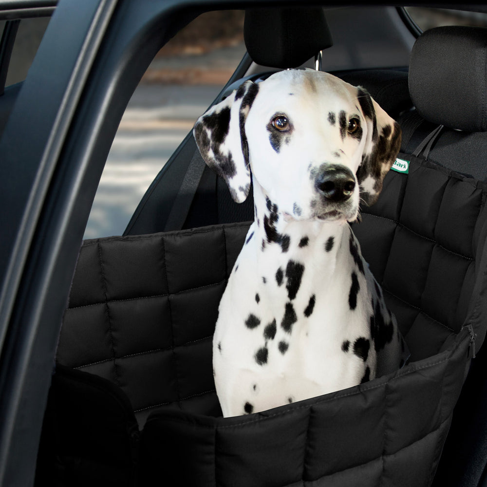 Dalmatiner sitzt auf einer gepolsterten Autodecke, die den Rücksitz schützt, schwarz und komfortabel für Hunde.