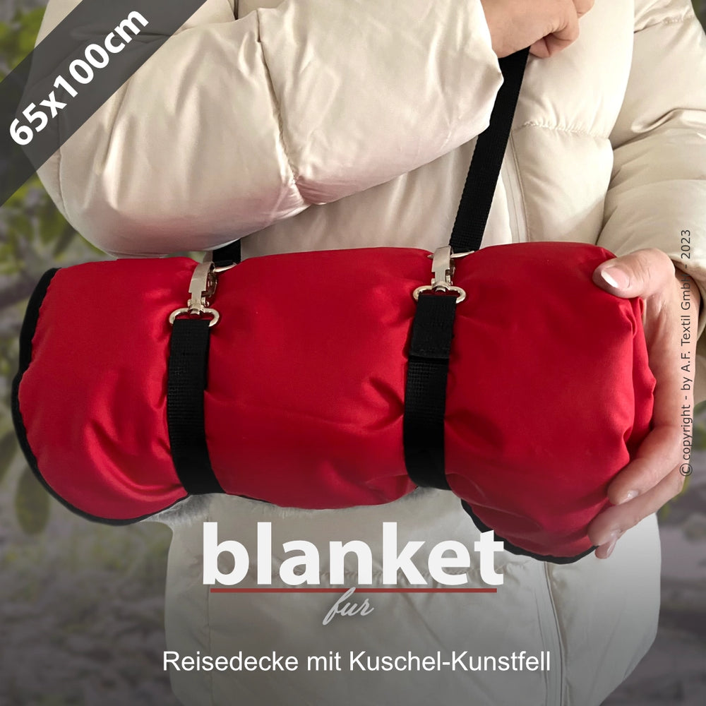 Aufgerollte rote Kuscheldecke aus Kunstfell mit Tragegurt, ideal für Reisen und gemütliche Abende. Größe 65x100 cm.