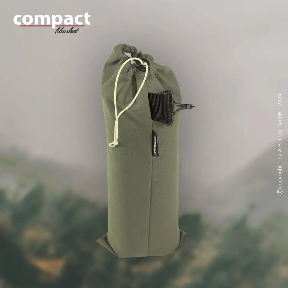 Kompakte grüne Tragetasche mit Kordelzugverschluss auf der Natur; ideal für Regenjacken oder Picknickdecken.