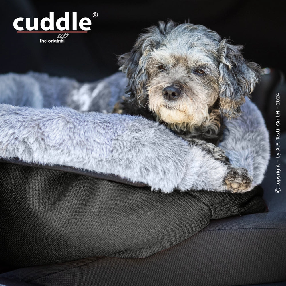 Kleiner Hund entspannt auf grauem, flauschigem Hundebett von cuddle.up®, ideal für gemütliche Ruheplätze.