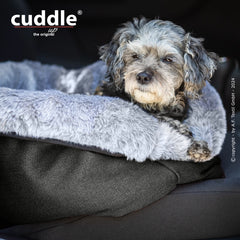 Kleiner Hund entspannt auf grauem, flauschigem Hundebett von cuddle.up®, ideal für gemütliche Ruheplätze.