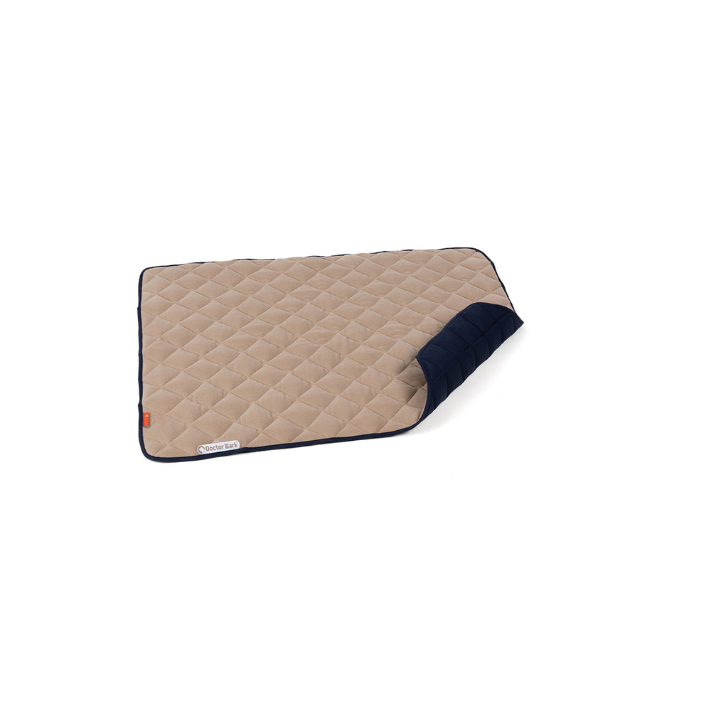 Beige Fleece-Steppdecke mit blauer Umrandung, diagonal gesteppt und leicht gefaltet. Ideal für gemütliche Abende.