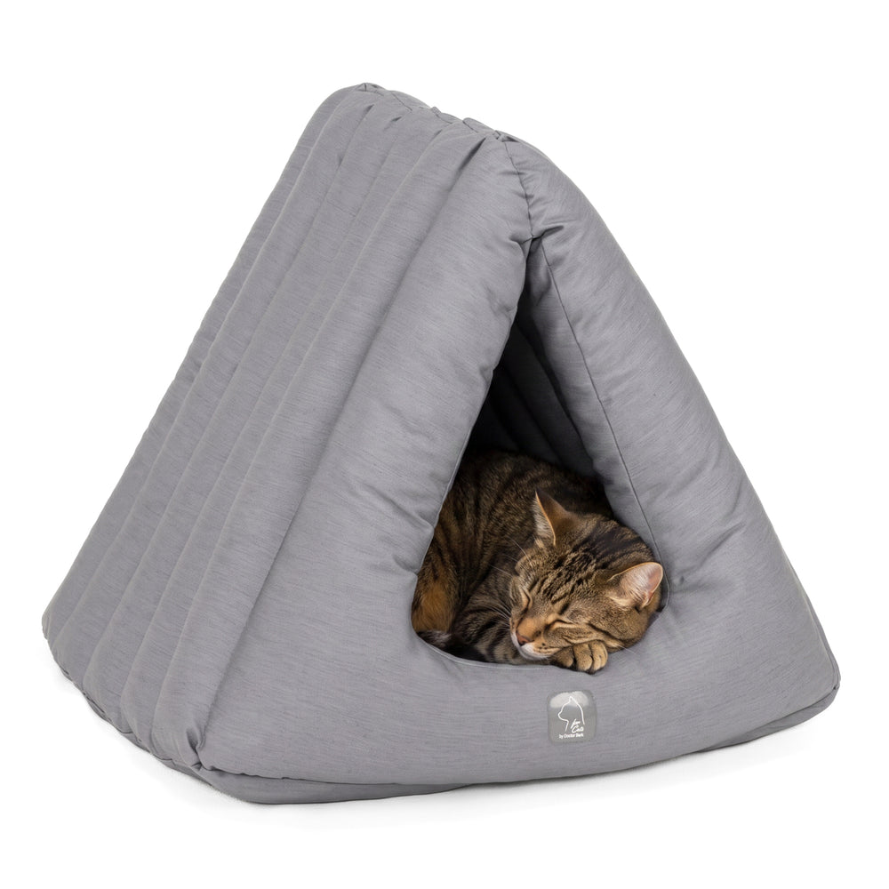 Graues, dreieckiges Katzenhaus aus weichem Stoff mit schlafender Katze im modernen, minimalistischen Wohnraum.