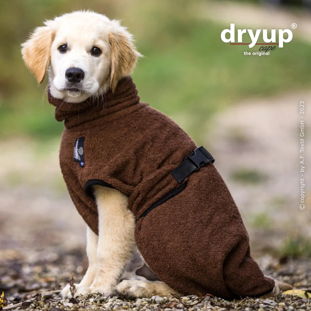 Golden Retriever Welpe im braunen Fleece-Hundebademantel von Dryup®, sitzt draußen und schaut zur Seite.