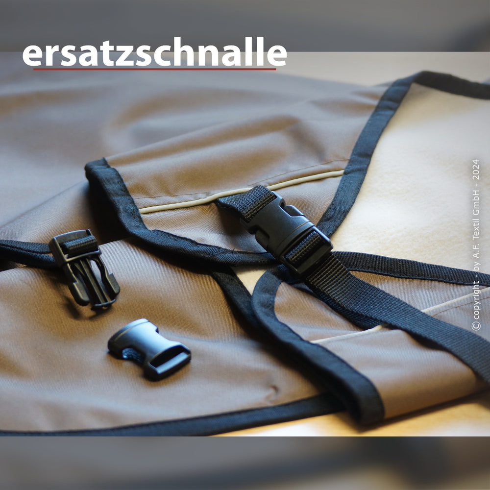 Ersatzschnalle aus schwarzem Kunststoff an braunem Textilmaterial mit dunklem Rand, zusätzlich sichtbares Kunststoffteil.